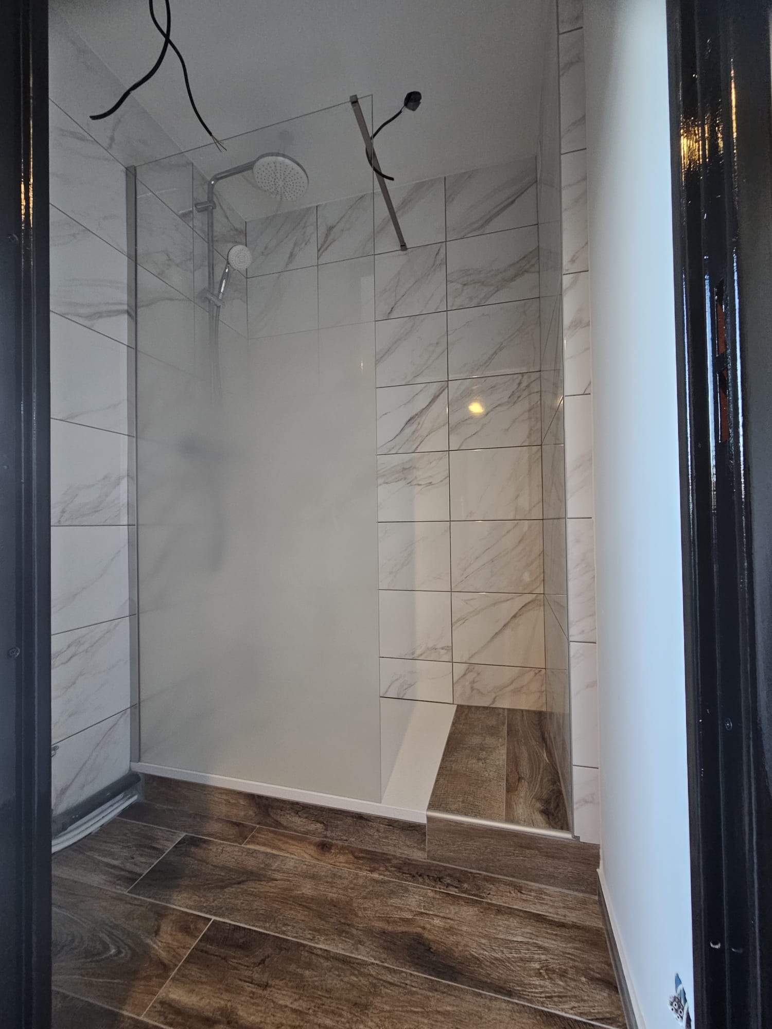 Douche à l'italienne carrelée effet marbre, paroi en verre et sol en carrelage imitation parquet